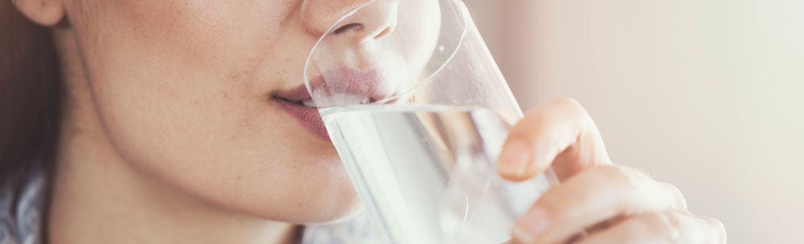 A woman is drinking a glass of water